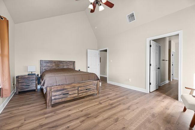 Bedroom with visible vents, baseboards, high vaulted ceiling, and wood finished floors | Image 25