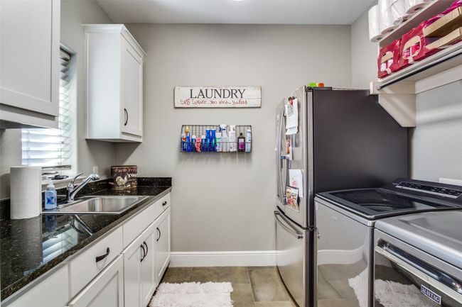 Washroom featuring baseboards, washing machine and dryer, cabinet space, and a sink | Image 25