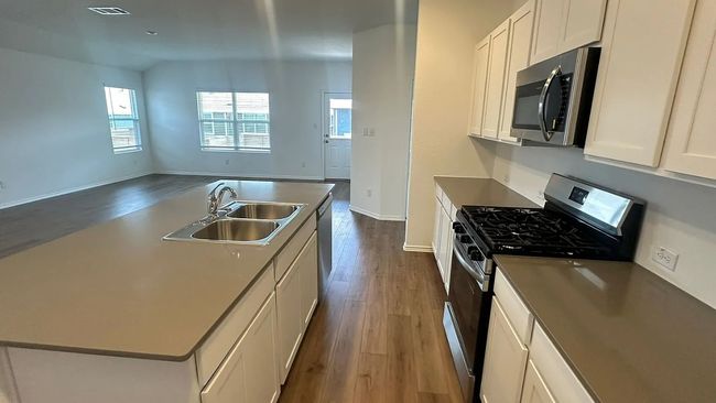 Kitchen with appliances with stainless steel finishes, dark wood-style floors, a kitchen island with sink, white cabinets, and lofted ceiling | Image 7