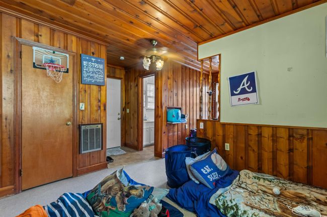 Bedroom with heating unit, wooden walls, a wainscoted wall, and wooden ceiling | Image 34