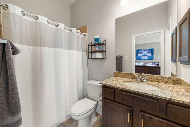 Secondary bathroom features granite countertops and dark cabinets, neutral paint, shower/tub combo with tile surround, large mirror, tile floors, sleek fixtures and plenty of space to accommodate any visiting family or guests. | Image 25