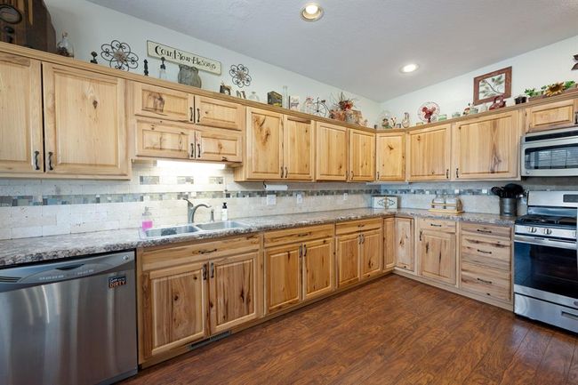 Kitchen with dark wood-type flooring, a sink, stainless steel appliances, and backsplash | Image 13