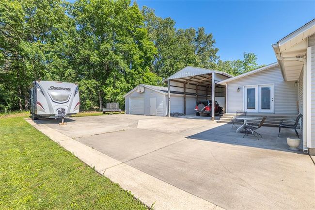 View of patio / terrace featuring a carport, an outdoor structure, and concrete driveway | Image 6