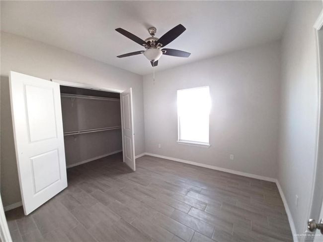 Unfurnished bedroom with baseboards, wood finished floors, a closet, and a ceiling fan | Image 5