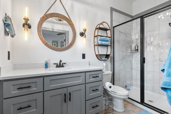 Full bath featuring toilet, vanity, and a marble finish shower | Image 17