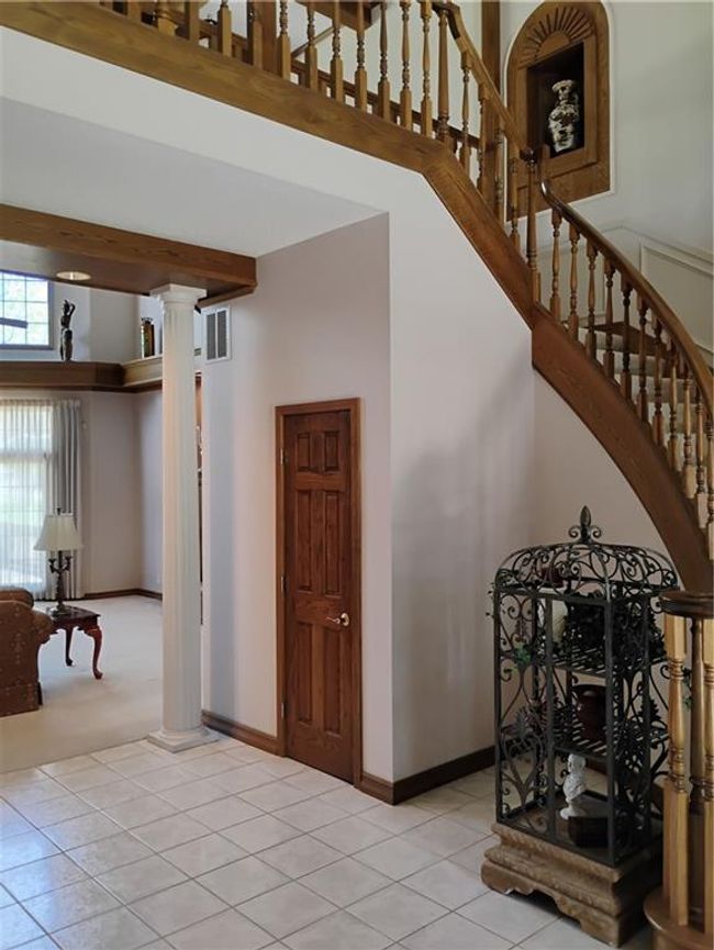 Stairway with tile patterned floors, storage closet a high ceiling, baseboards, and decorative stair columns | Image 15