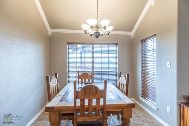 Dining space with crown molding, a chandelier, plenty of natural light, and baseboards | Image 12