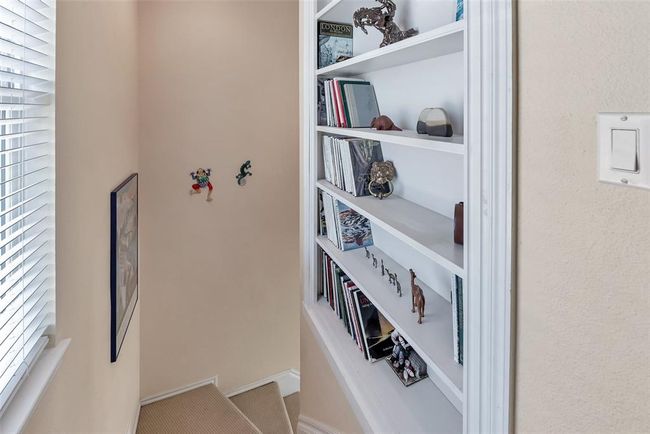 Tucked along the stairway landing, this custom built-in shelving adds character and function, perfect for displaying books, art, or collected keepsakes. A thoughtful touch that makes the space feel like home. | Image 16