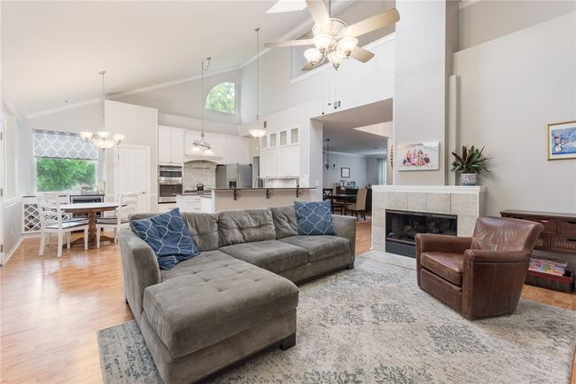 Living area with high vaulted ceiling, light wood finished floors, ceiling fan, plenty of natural light, and ornamental molding | Image 11