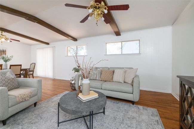 Living area featuring a ceiling fan, wood finished floors, beamed ceiling, and baseboards | Image 7