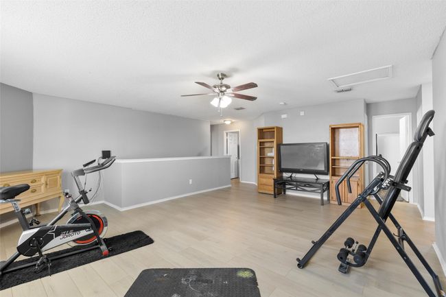 Workout area featuring light wood-type flooring, ceiling fan, a textured ceiling, and attic access | Image 19