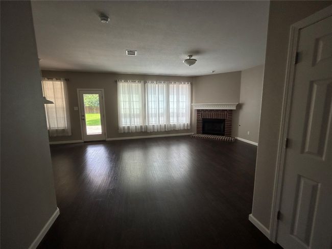 Unfurnished living room featuring baseboards, dark wood finished floors, and a fireplace | Image 9