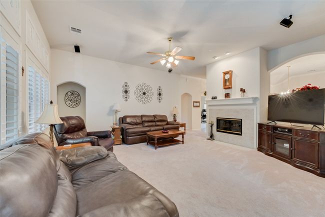 Living area featuring arched walkways, ceiling fan, carpet flooring, and a high end fireplace | Image 10