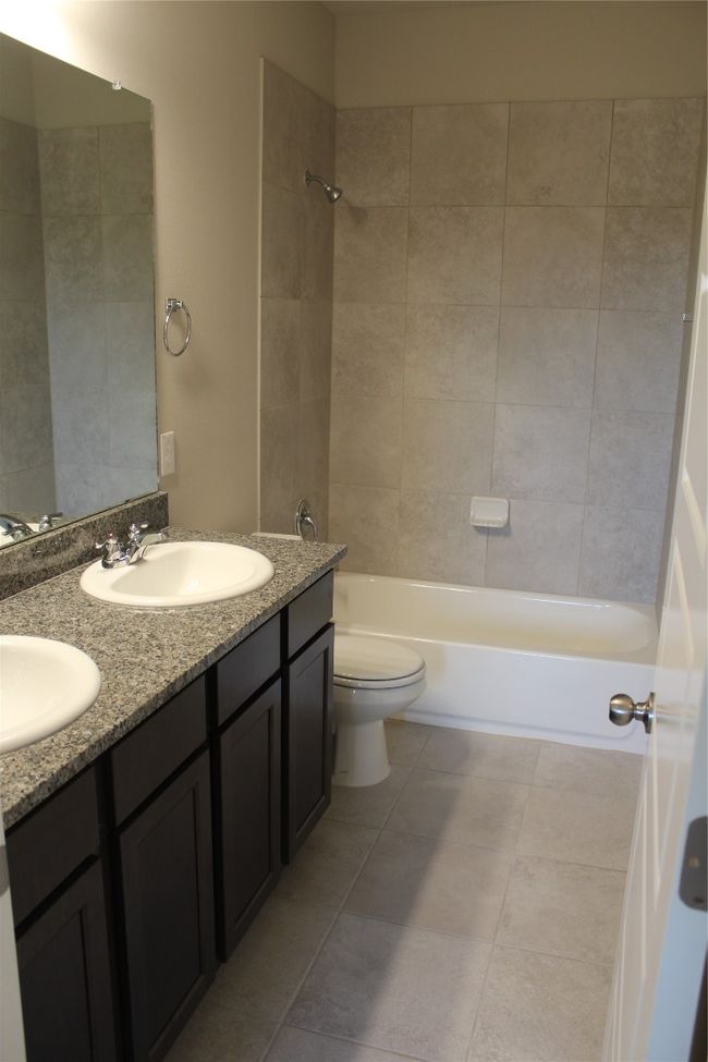 Bathroom with double vanity, shower / bathtub combination, toilet, and tile patterned floors | Image 15