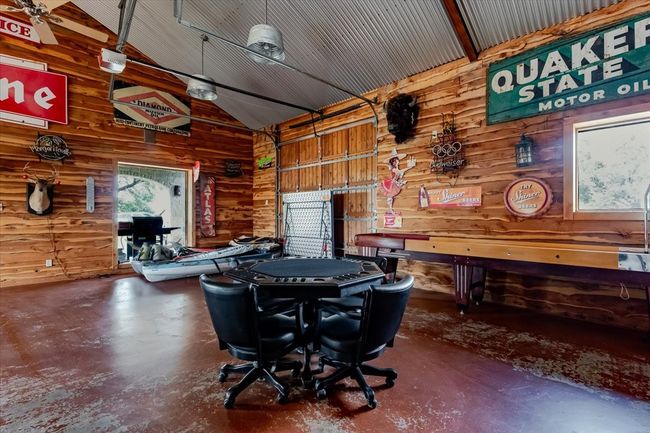 Playroom featuring wooden walls, lofted ceiling, finished concrete flooring, and a garage | Image 10