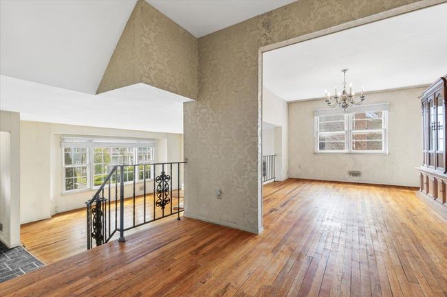 Empty room featuring wood-type flooring, a wealth of natural light, a notable chandelier, and wallpapered walls | Image 7