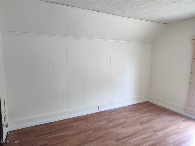 Additional living space featuring wood finished floors, baseboards, lofted ceiling, and a textured ceiling | Image 37