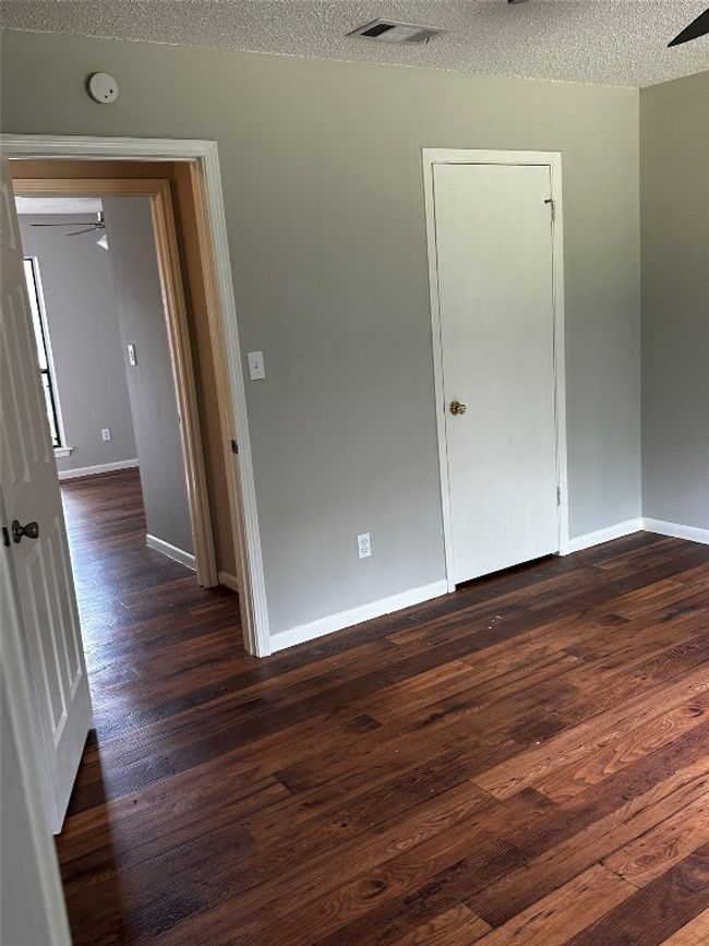 Unfurnished room with a ceiling fan, a textured ceiling, and dark wood-style flooring | Image 13