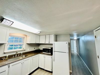 Kitchen with sink, light hardwood / wood-style floors, a textured ceiling, white cabinetry, and white fridge | Image 3