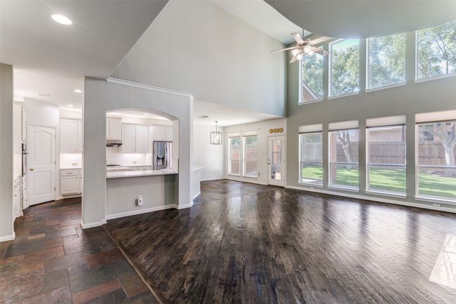 Unfurnished living room with ceiling fan, plenty of natural light, a towering ceiling, recessed lighting, and arched walkways | Image 5