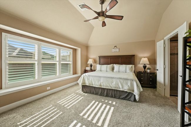 Carpeted bedroom with lofted ceiling, visible vents, baseboards, and ceiling fan | Image 19
