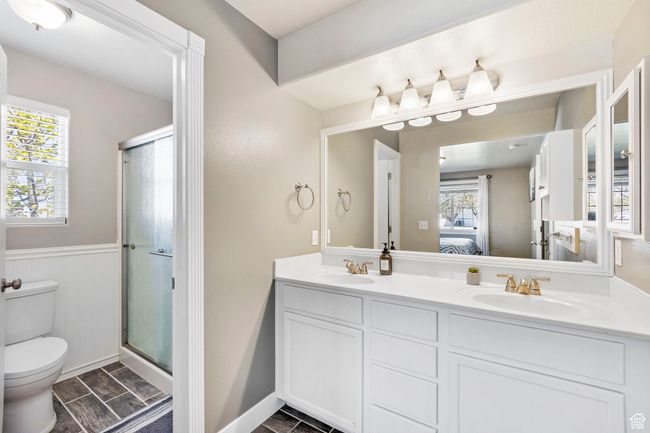 Ensuite bathroom featuring double vanity, a sink, connected bathroom, and toilet | Image 19
