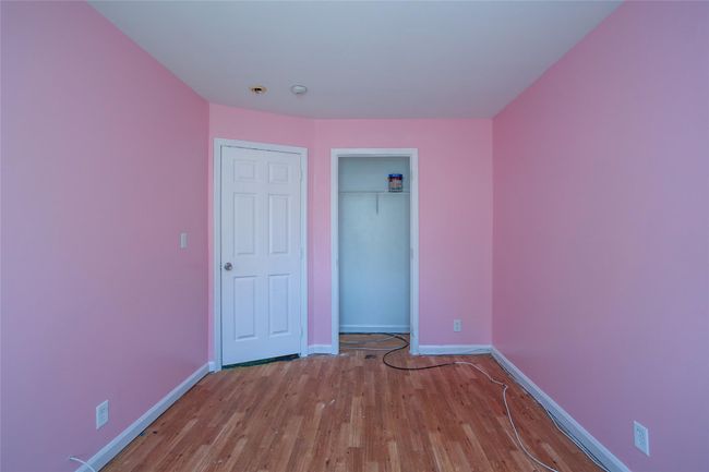 Unfurnished bedroom with baseboards, wood finished floors, and a closet | Image 10