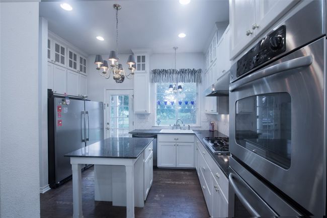 Kitchen featuring stainless steel appliances, a chandelier, dark wood finished floors, backsplash, and under cabinet range hood | Image 11