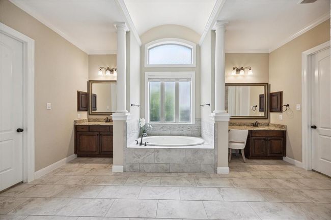Spa-Like Primary Bathroom with stunning columns, double sinks, vanity, large jacuzzi tub, and 2 very large walk-in closets with custom storage built ins | Image 22