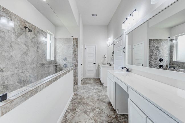 The spa-inspired ensuite bath is a serene retreat crafted for ultimate relaxation and indulgence. Dual vanities offer generous space, while the elegant walk-in shower, adorned with neutral-toned tiles, creates a luxurious and calming ambiance. | Image 16