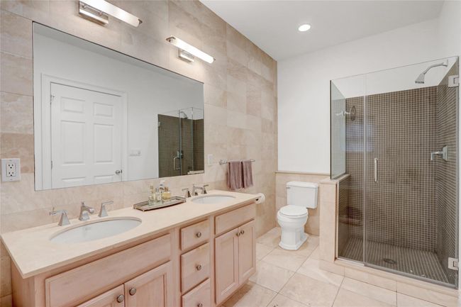 Full bath with tile walls, double vanity, tile patterned floors, a stall shower, and toilet | Image 16