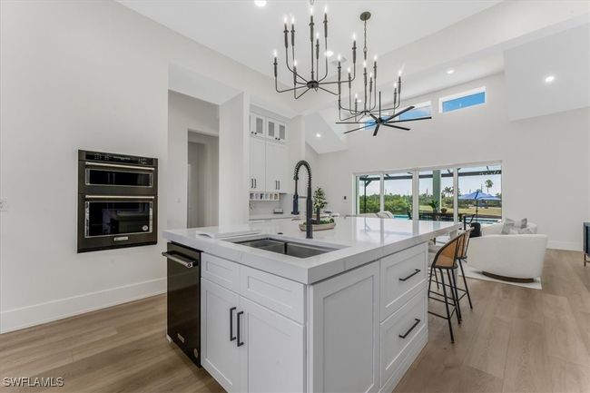 Kitchen featuring a chandelier, open floor plan, light countertops, white cabinets, and recessed lighting | Image 7