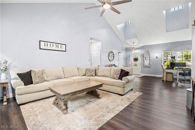 Living room with high vaulted ceiling, dark wood-type flooring, ceiling fan, and a skylight | Image 10
