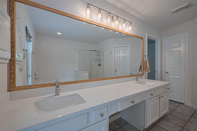 Enjoy a separate jetted soaking tub, updated standalone shower, upgraded quartz countertops, and all-new sinks, faucets, and vanity lights—plus the convenience of a private door leading to the backyard. | Image 20