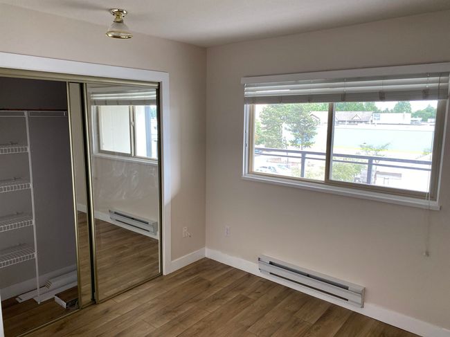 Unfurnished bedroom featuring a baseboard radiator, dark wood-type flooring, and baseboards | Image 5