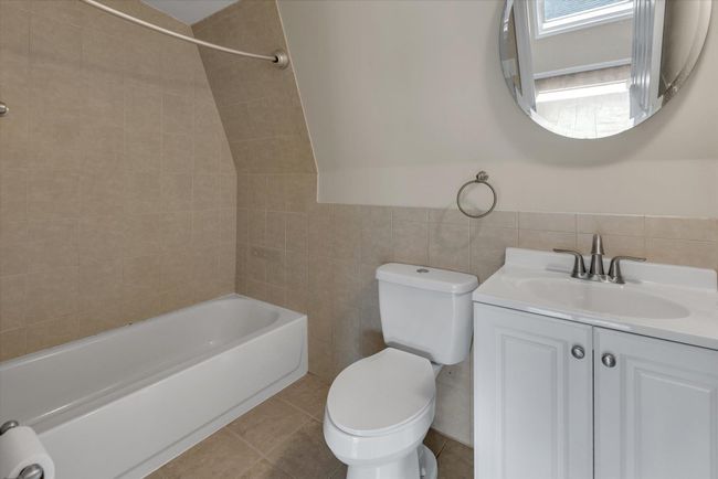 Bathroom featuring tile walls, toilet, shower / bath combination, tile patterned floors, and vanity | Image 12