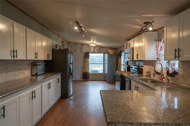 Kitchen with stainless steel appliances, backsplash, light wood-type flooring, and rail lighting | Image 15