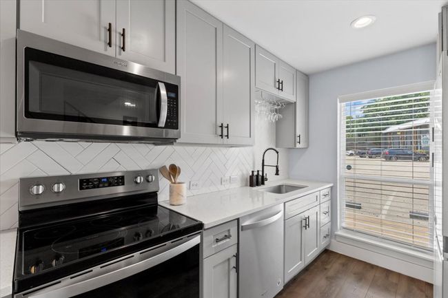Kitchen featuring appliances with stainless steel finishes, light countertops, decorative backsplash, dark wood finished floors, and recessed lighting | Image 9