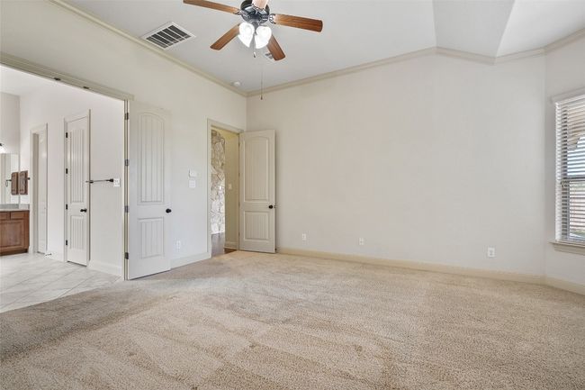 Unfurnished bedroom featuring ornamental molding, light carpet, ensuite bath, and a ceiling fan | Image 28