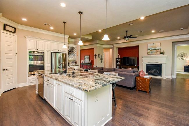The stainless appliances include double ovens, gas cooktop and dishwasher! There is a cabinet that slides out to conceal trash cans as well! | Image 19