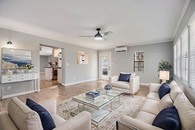 Living area featuring an AC wall unit, light wood finished floors, a ceiling fan, and crown molding | Image 10