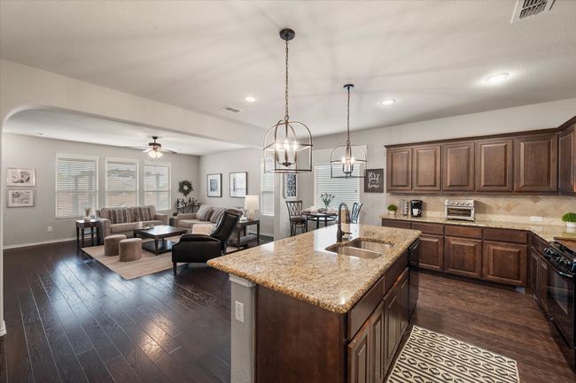 Kitchen with light stone countertops, gas stove, a sink, and visible vents | Image 12