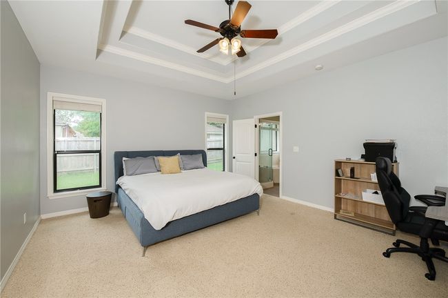 Carpeted bedroom featuring crown molding, connected bathroom, a raised ceiling, and baseboards | Image 15