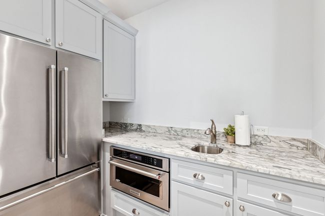 Kitchen featuring white cabinetry, a sink, stainless steel appliances, and light stone countertops | Image 25