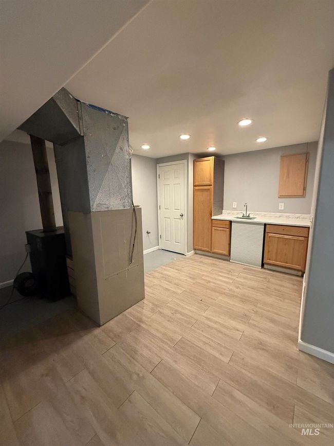 Kitchen with light wood-type flooring, recessed lighting, light countertops, a wood stove, and brown cabinets | Image 27