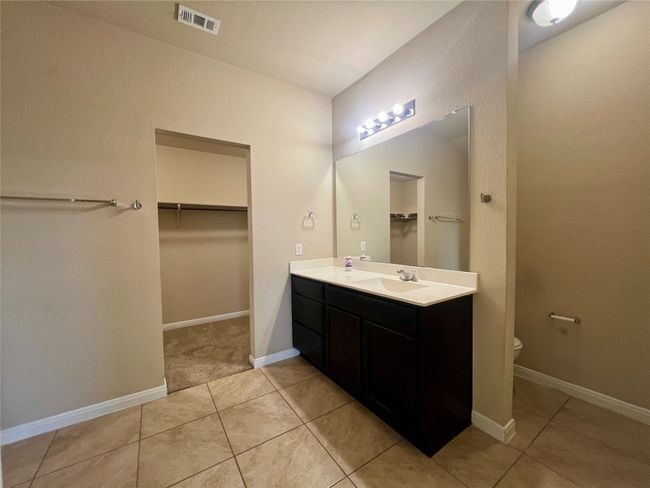 Full bath featuring a spacious closet, double vanity, toilet, tile patterned flooring, and baseboards | Image 14