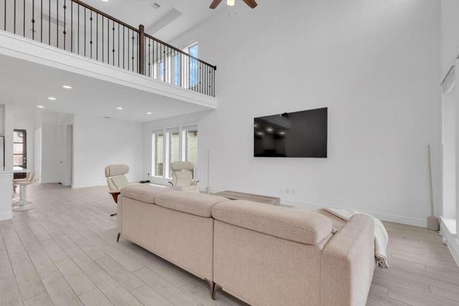 Living area featuring a high ceiling, light wood finished floors, recessed lighting, and a ceiling fan | Image 20