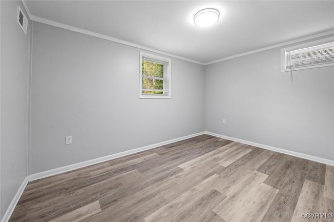 Empty room featuring wood finished floors, visible vents, crown molding, and baseboards | Image 29