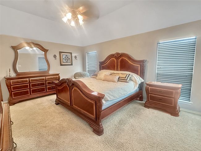 Bedroom featuring light carpet, ceiling fan, vaulted ceiling, and baseboards | Image 5