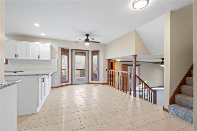 Kitchen featuring white cabinets, light tile patterned floors, baseboards, and ceiling fan | Image 13